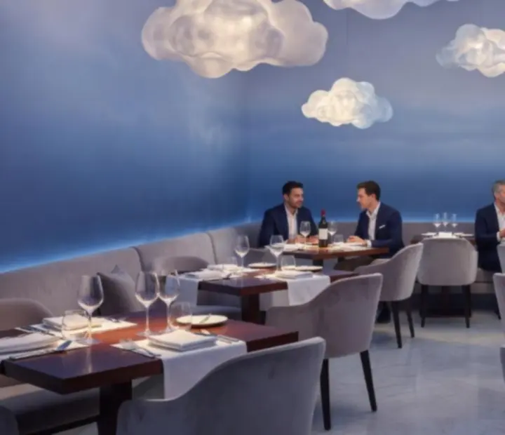 Décor lumineux avec nuages suspendus et jeux de lumière sur les tables